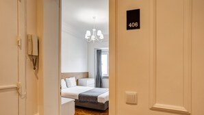Une chambre d’hôtel avec un lit, une table de chevet, un lustre et une fenêtre avec des rideaux.