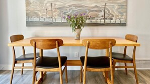 A dining area with a wooden table and chairs, a vase with flowers, and a large abstract painting on the wall. - ‘Garden House’ - Beautiful Mid-Century Home (Tucson)