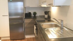 Una cocina moderna con electrodomésticos de acero inoxidable, una cafetera y un lavamanos.