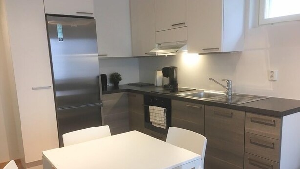 Una cocina moderna con electrodomésticos de acero inoxidable, una mesa de comedor blanca y un fregadero.