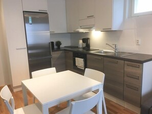 A modern kitchen with stainless steel appliances, a white dining table, and a sink. - Kotimaailma Apts Joensuu Kalevankatu 20 (Joensuu)