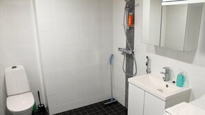 A bathroom with a toilet, a shower, and a sink. - Kotimaailma Apts Joensuu Koskikatu 11 (Joensuu)