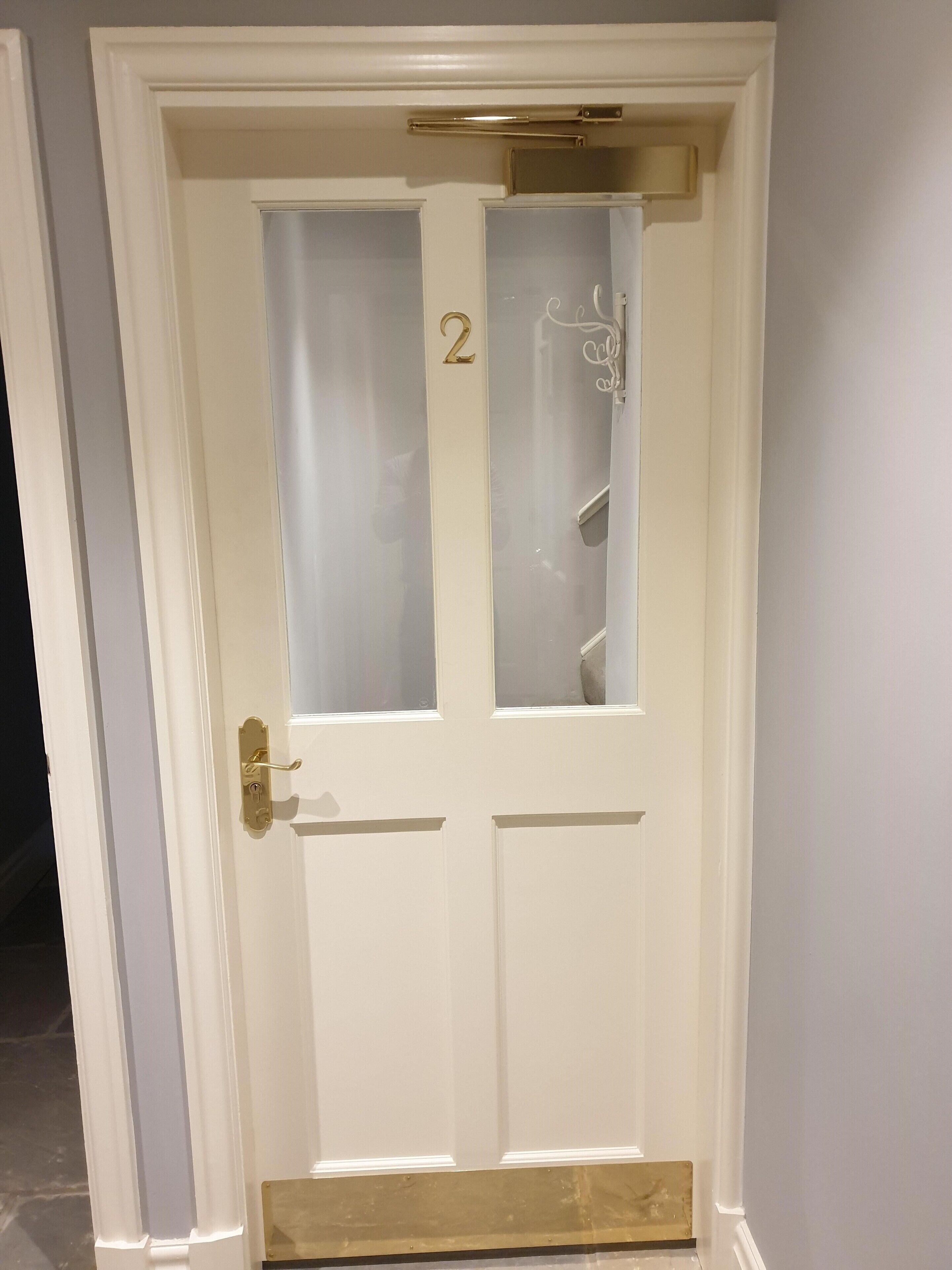 A white door with a glass panel, a brass handle, and a number '2' above the glass.