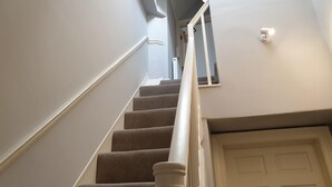 A staircase with carpeted steps, white handrails, and a white door at the bottom. - 71 Micklegate - Apartment 2 (York)