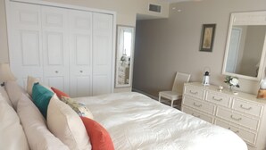 Une chambre à coucher avec un grand lit, une commode, une chaise et un miroir.