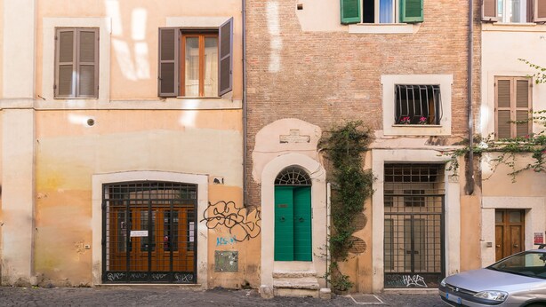 Un bâtiment avec une porte verte, une fenêtre grillagée et une enseigne sur la porte.