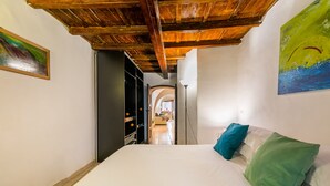Une chambre avec un plafond en bois, un lit agrémenté d’oreillers blancs et turquoise, et un tableau accroché au mur.