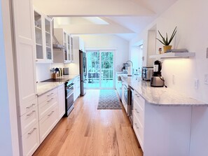Een moderne keuken met witte kasten, een ingebouwde oven, een koelkast en een koffieapparaat.