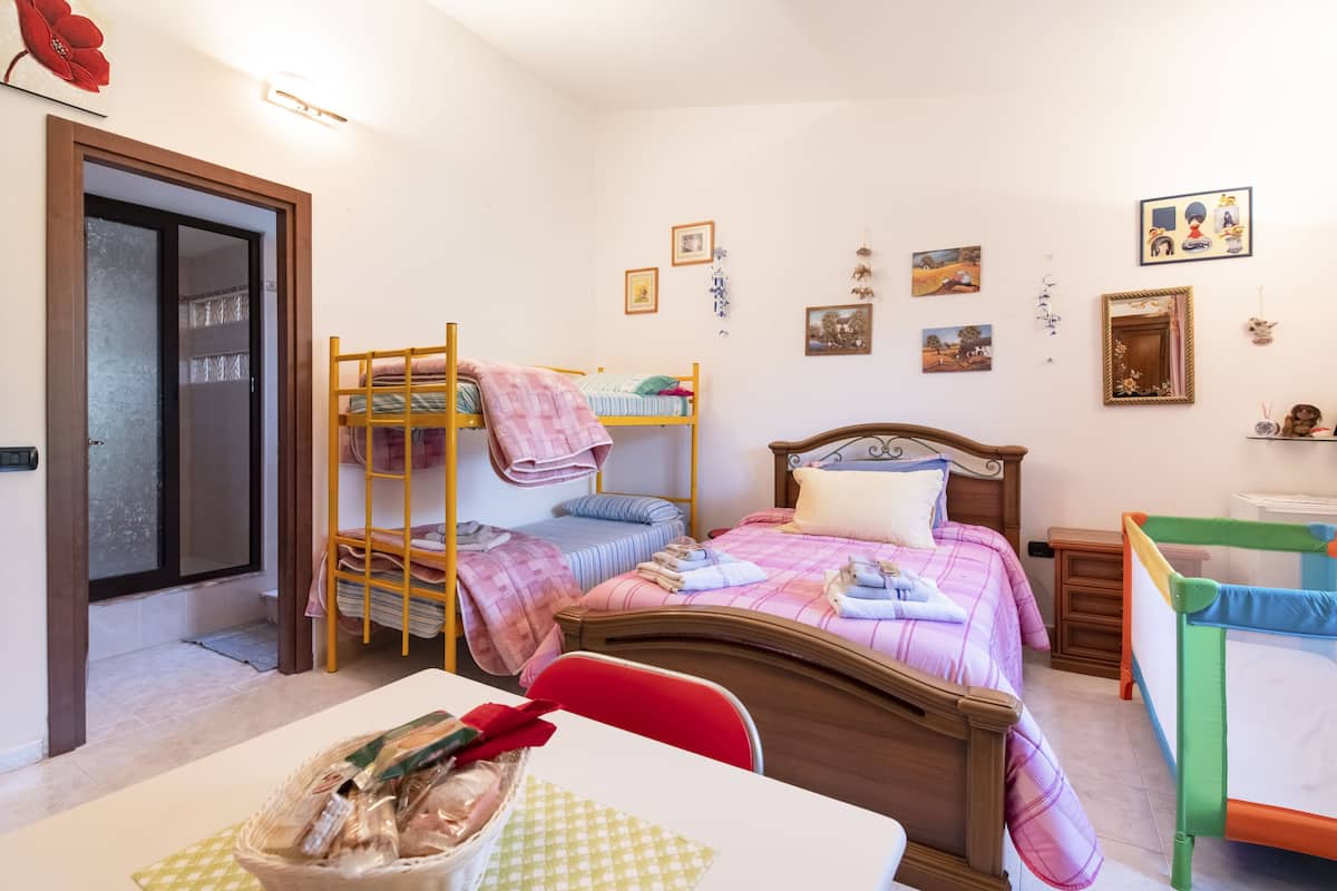 A bedroom with bunk beds, a wooden headboard, a bedside table with a basket of items, and a small bedside table with a mirror.