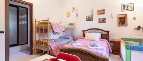 A bedroom with bunk beds, a wooden headboard, a bedside table with a basket of items, and a small bedside table with a mirror.