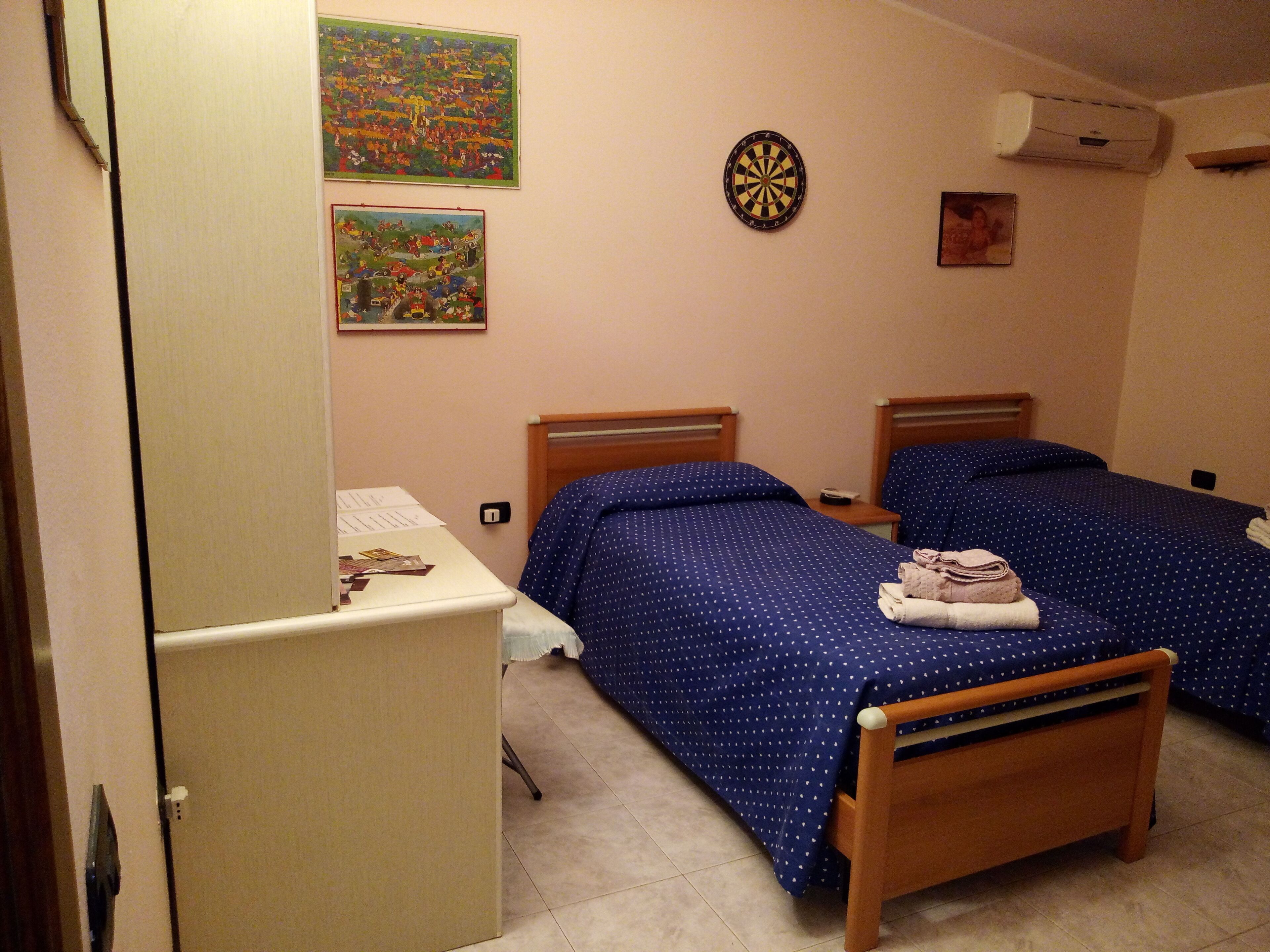 Habitación de hotel con dos camas, un escritorio y un armario.