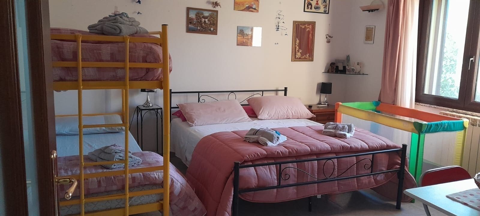 Une chambre de dortoir avec des lits superposés, un lit simple, un bureau et une fenêtre avec des rideaux.