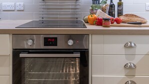 Eine moderne Küche mit Einbauofen, Edelstahl-Dunstabzugshaube und einer Arbeitsplatte mit verschiedenen Küchenutensilien.