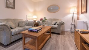 Ein Wohnzimmer mit zwei Sofas, einem Couchtisch, einer Lampe, einem Spiegel und einer Heizung.