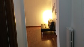 A hallway with a wooden floor, a black sofa, and a radiator. - Nice and comfortable 55 square meter apartment in the center of Avellino (Avellino)