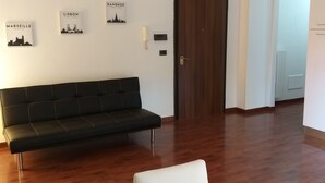 A modern living room with a black sofa, a white coffee table, and a blue bowl with straws. There are wall-mounted pictures of cities and a door in the background. - Nice and comfortable 55 square meter apartment in the center of Avellino (Avellino)