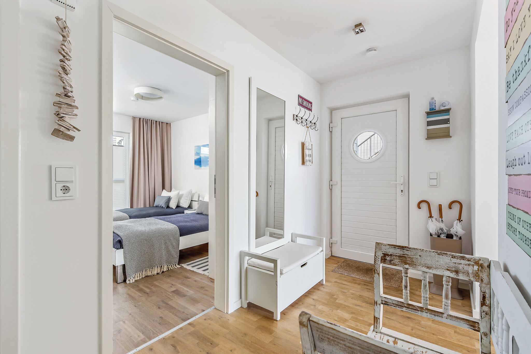 A modern, well-lit room with a bed, a small desk, and a mirror.