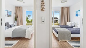 A modern bedroom with two beds, a large window, and a view of the outdoors.