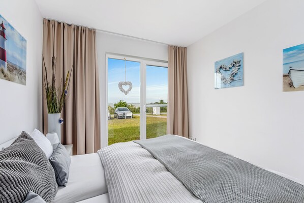 Un dormitorio con cama, cortinas, una decoración con forma de corazón y vistas al exterior.