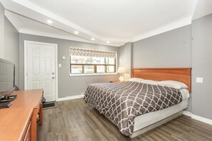 A bedroom with a bed, a desk, a chair, a window with a view, and a door. - Haven Inn (Hamilton)