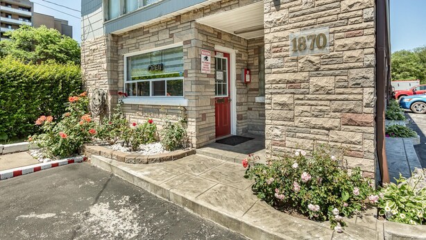 A building with a stone facade, a red door, and a sign indicating an office. - Haven Inn (Hamilton)
