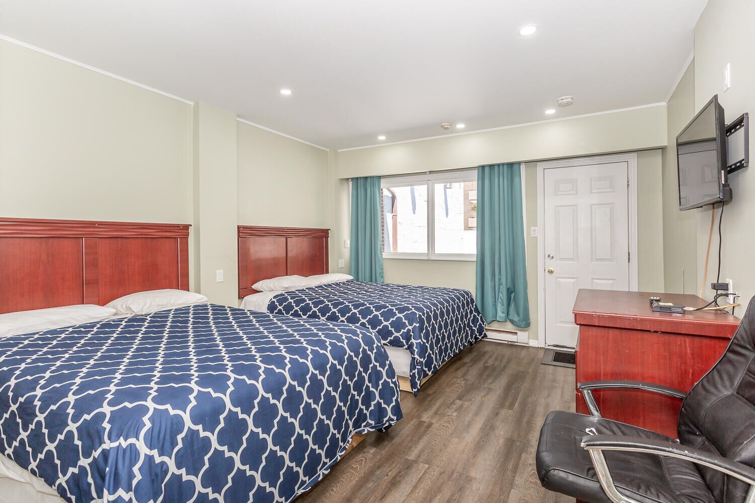 Una habitación de hotel con dos camas, un escritorio, una silla y un televisor.