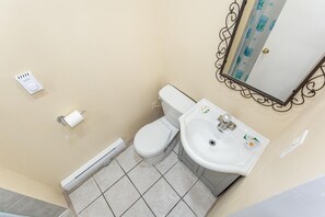 A small bathroom with a toilet, sink, and a mirror with a decorative frame. - Haven Inn (Hamilton)