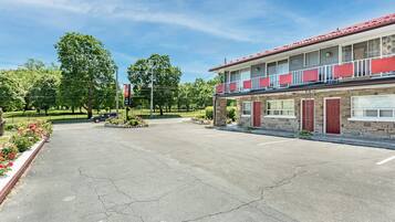 Un motel composé d’un bâtiment à deux étages, d’un parking et d’un espace paysager agrémenté d’arbres et de fleurs.