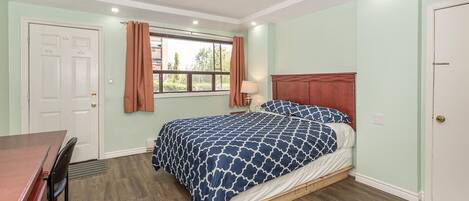 Une chambre à coucher avec un lit, un bureau et une fenêtre avec des rideaux.