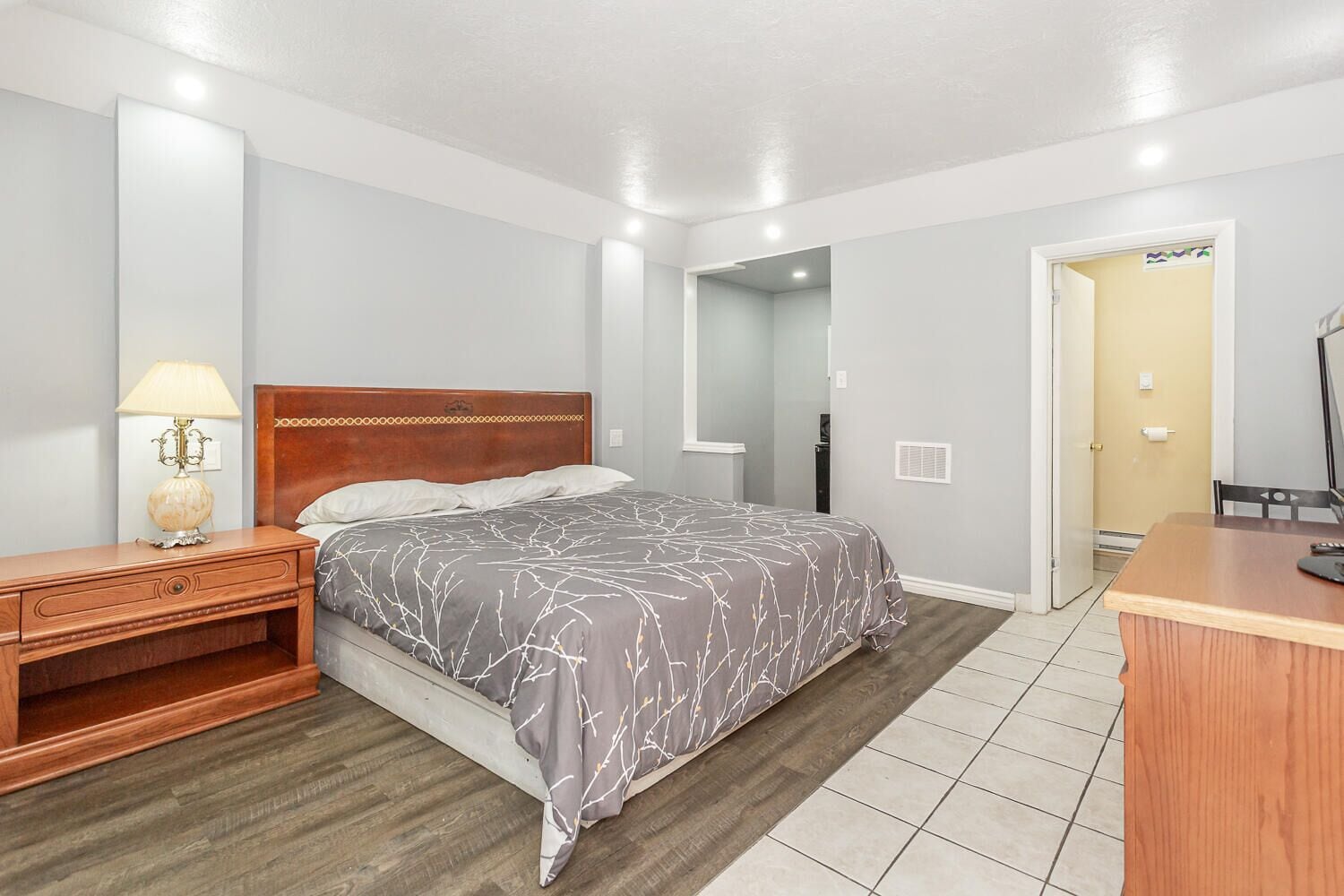 Un dormitorio con cama, mesita de noche, lámpara y un escritorio con silla.
