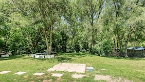A backyard with a wooden deck, a grassy lawn, and trees. - Haven Inn (Hamilton)