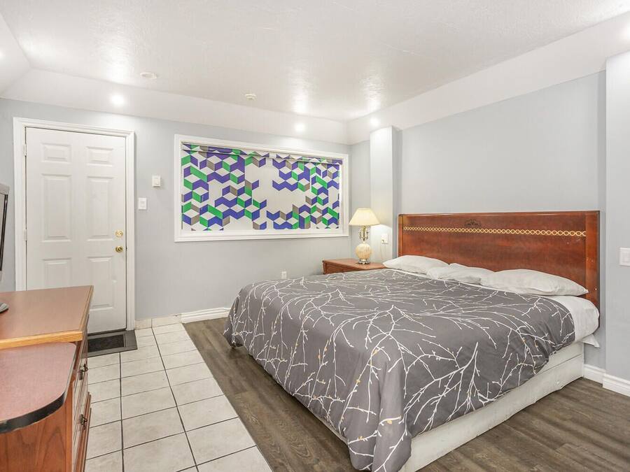 Un dormitorio con cama, escritorio, televisión y una obra de arte con diseño geométrico en la pared.