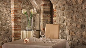 Una mesa lista para comer en una habitación con paredes de ladrillo visto y techo de piedra.