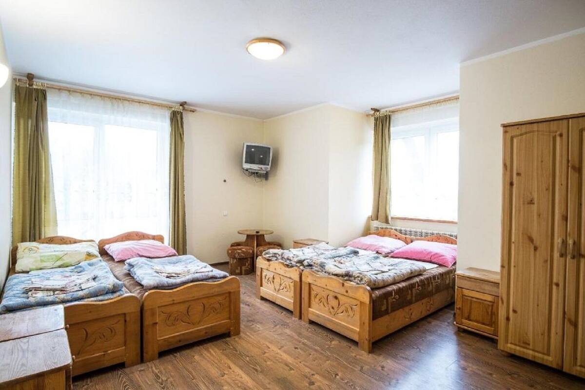 A bedroom with two wooden beds, a TV on the wall, and a wooden wardrobe.