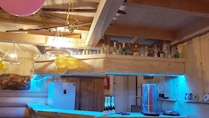 A bar area with a stone counter, a refrigerator, and shelves with bottles. - Willa Sport (Zakopane)