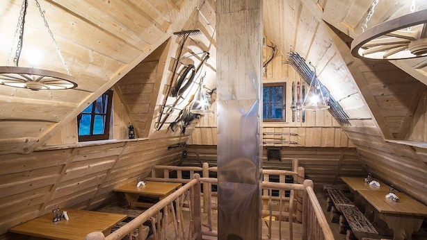 A wooden cabin interior with a central staircase, wooden tables, and a large metal beam. - Willa Sport (Zakopane)