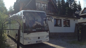 A white bus parked in front of a building with a balcony and a sign that reads "WILLA SPORT". - Willa Sport (Zakopane)