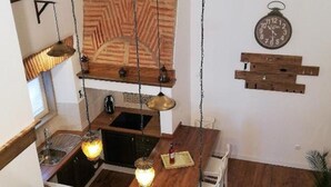 Una cocina compacta con armarios de madera, una lámpara colgante y un reloj en la pared.