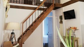 Una escalera con barandillas de madera e iluminación colgante, que sube a un piso superior.