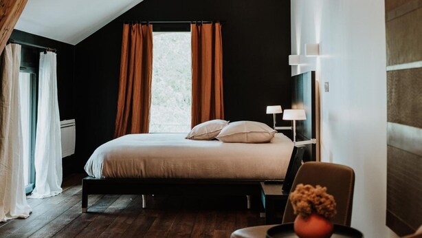 A bedroom with a sloped ceiling, a bed with pillows, a chair with a vase, and a bedside table with a lamp. - Le clos de la Pomponnette (Pomponne)