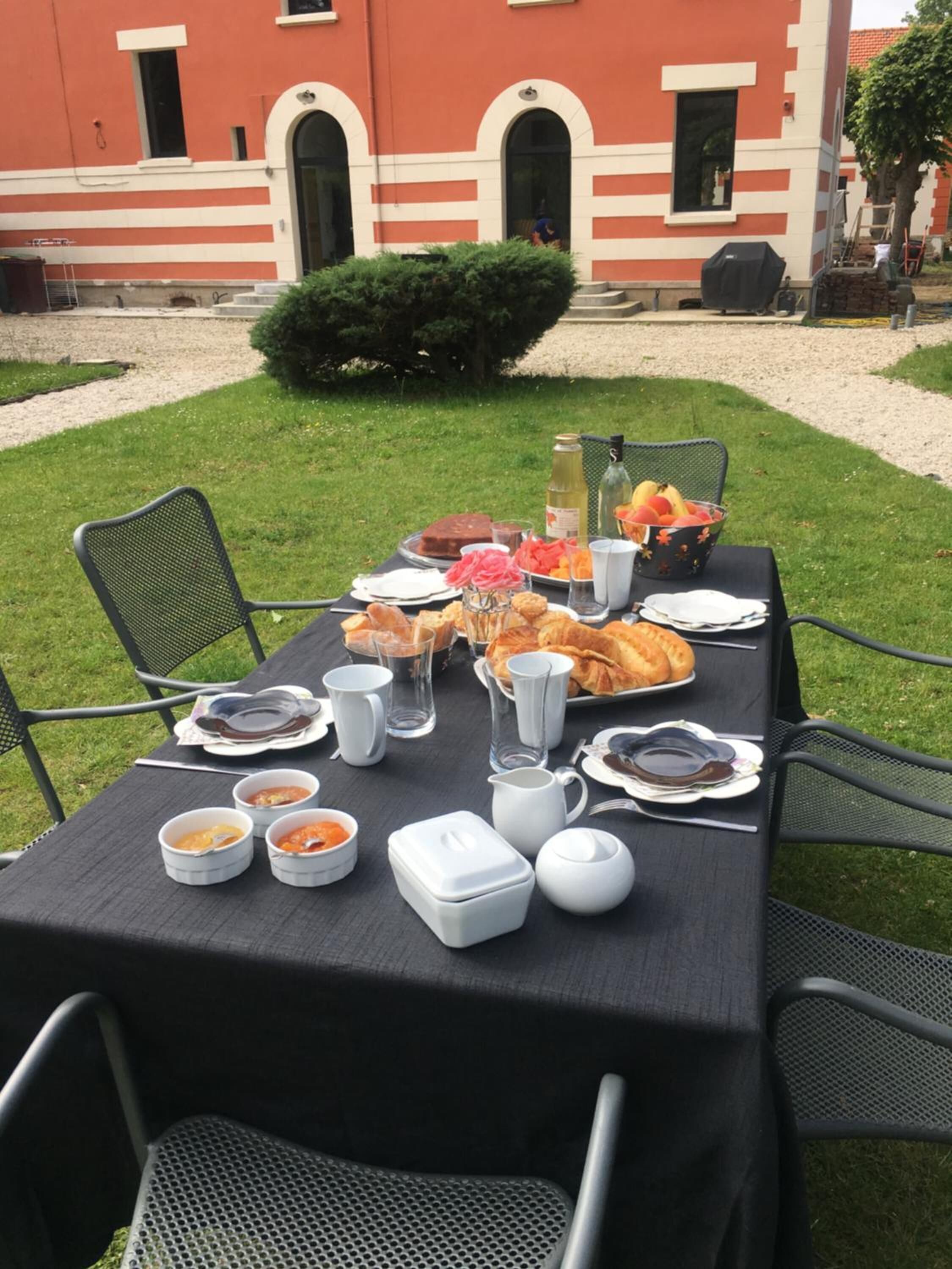 An outdoor dining setup with a table set for two, featuring a variety of dishes and drinks.