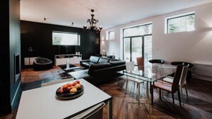 A modern living room with a black sofa, a glass coffee table, and a dining area with a glass table and chairs. - Le clos de la Pomponnette (Pomponne)