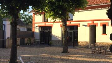 A courtyard with a building featuring a tiled roof, benches, and trees.