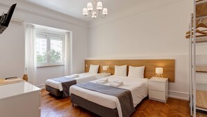 Hotellihuone, jossa on kaksi sänkyä, työpöytä, televisio ja kattokruunu.
