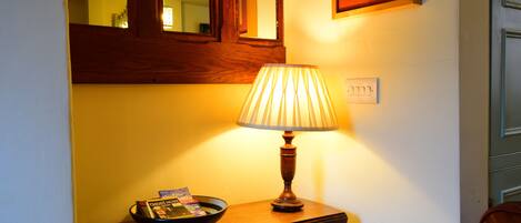 Una mesita de noche de madera con una lámpara y un cuenco con revistas.
