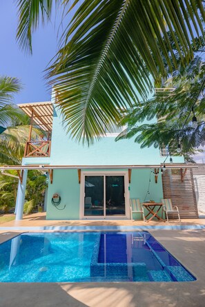 A two-story building with a swimming pool, a covered patio, and a view of palm trees. - Chic Beach House w/ Pool, A/C & Penthouse near La Punta – Walk to the Ocean! (Puerto Escondido)
