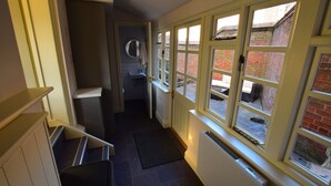 A narrow hallway with a radiator, a door leading to a room, and a window with a view of a brick building. - 14 St Saviour's Place (York)