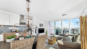 A modern living space with a dining area, kitchen, and seating area with a view of the harbor. - Water house "Villa Sansibar" - special Baltic Sea vacation with roof terrace and sauna (Olpenitz)
