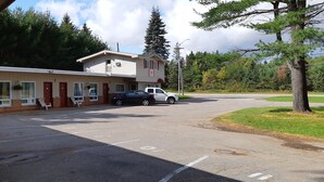 A motel with a two-story building, a parking lot, and a row of yellow chairs outside. - Pine Grove Motel (Sault Ste. Marie)