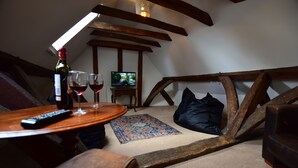A cozy room with a wooden ceiling, a television, a bottle of wine, and two glasses on a table. - 87 Micklegate (York)